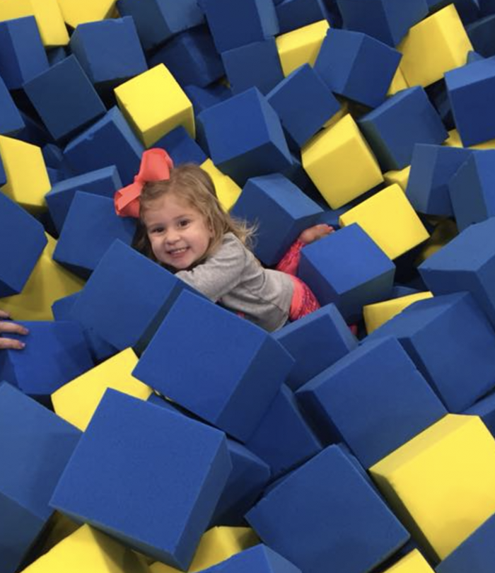 Little girl smiles in foam cube pit.