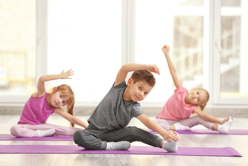 Group of children doing gymnastics exercises on mats