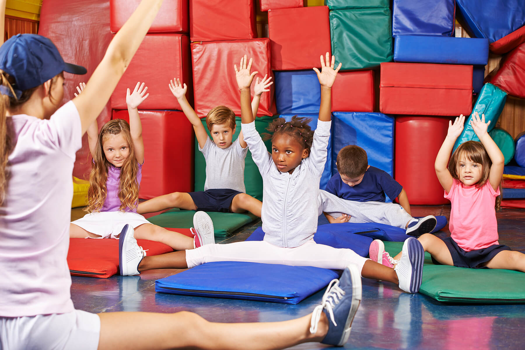 Children taking gymnastics class with instructor teaching